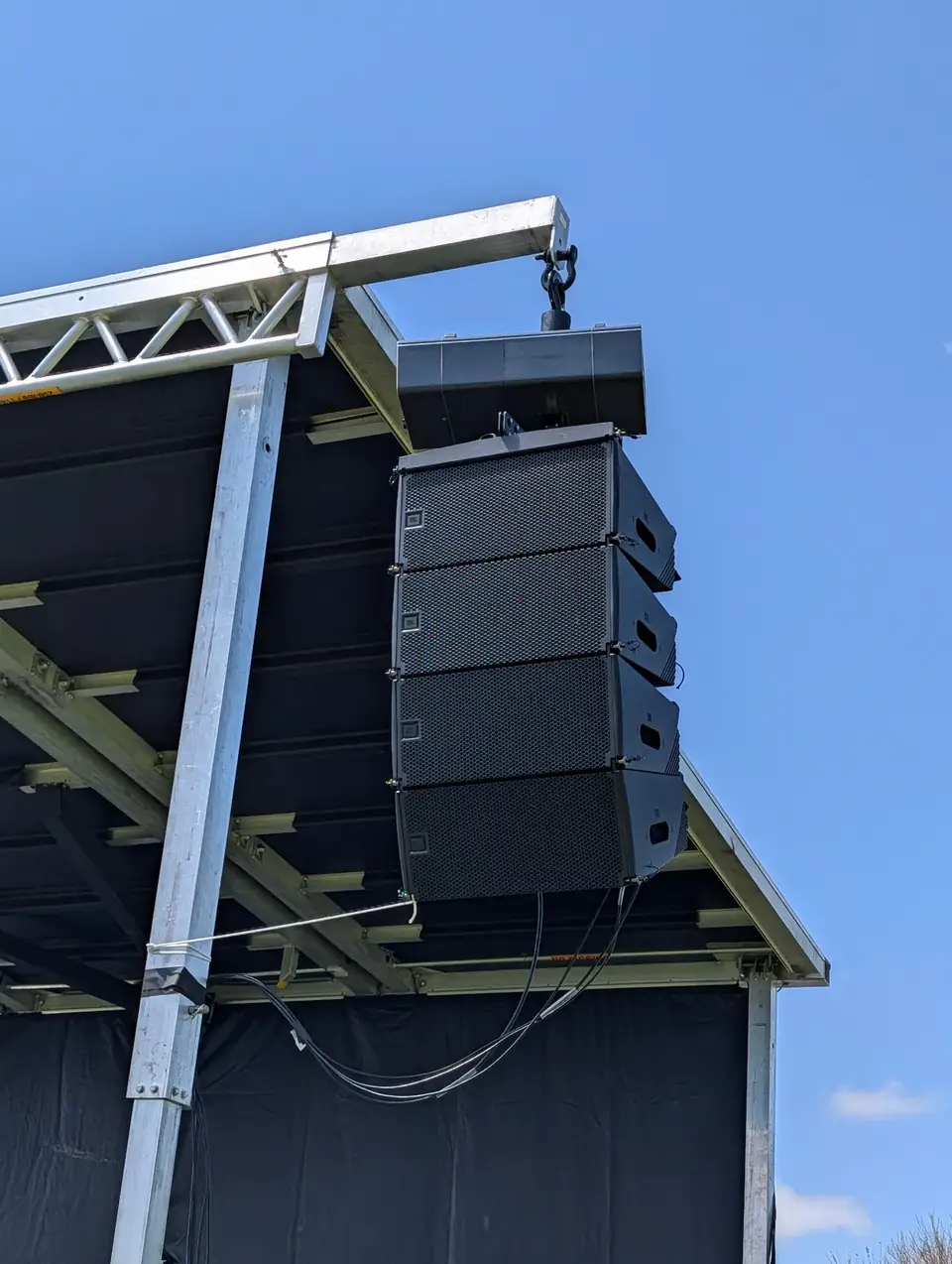 Line-array speakers hanging from outdoor stage truss