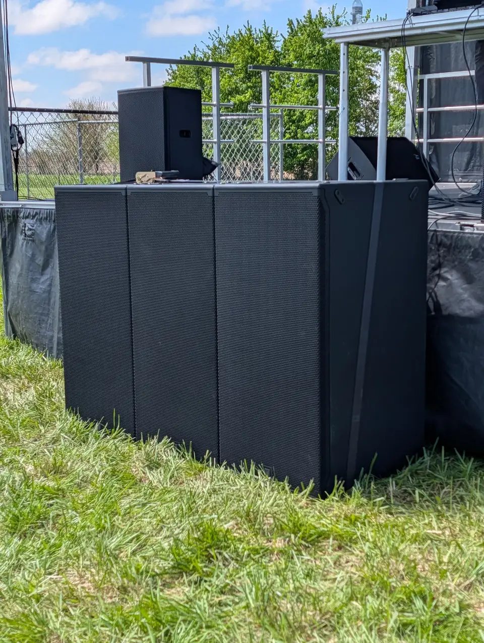 JBL subwoofers stacked beside an outdoor stage