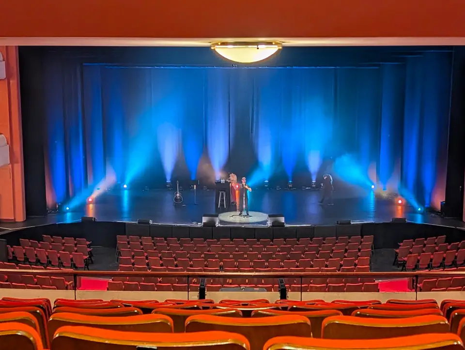 Theater auditorium with a blue-lit stage during the Kevin James tour